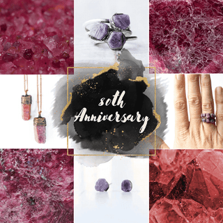 Raw ruby gemstones and sterling silver jewelry set against a rustic wood background